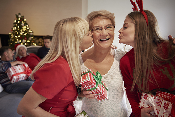 daughters kissing mom with christmas gift